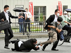 This image received from the Asahi Shimbun newspaper shows a man (centre R) suspected of shooting former Japanese prime minister Shinzo Abe being tackled to the ground by police at Yamato Saidaiji Station in the city of Nara on July 8, 2022.