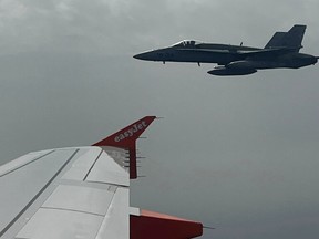 Spanish F-18 jet fighter, seen through plane window, escorts an Easyjet flight heading from London to the Spanish holiday island of Menorca, after a hoax bomb threat by an 18-year-old British passenger, July 3, 2022.