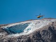 A rescue helicopter flies on July 4, 2022 over the glacier that collapsed the day before on the mountain of Marmolada, the highest in the Dolomites, one day after a record-high temperature of 10 degrees