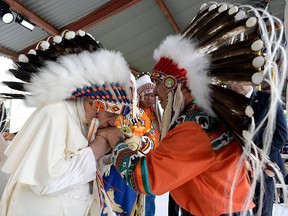 Pope Francis kisses the hands of Chief Wilton Littlechild after receiving a headdress during a visit to Maskwacis, Alta., on July 25, 2022.