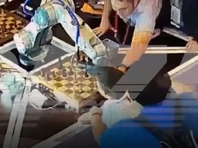 In this still shot taken from a video, adults can be seen trying to help a child after a chess-playing robot crushes his finger.
