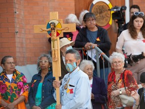 Elmer Waniandy holds a cross to lead a procession into Sacred Heart Church of the First Peoples for a rededication service on July 17, 2022. The Edmonton church, which is undergoing repairs and renovations, was badly damaged by fire in August 2020. Pope Francis will be visiting the Indigenous-Catholic church next week.