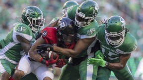 REGINA, SASK : July 8, 2022 -- A trio of Saskatchewan Roughriders defenders tackle a Ottawa Redblacks player at Mosaic Stadium on Friday, July 8, 2022 in Regina.