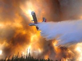 In this photo provided by Eric Kiehn, Northwest Incident Management Team 10, Alaska Division of Forestry, a fixed-wing aircraft drops water on the Clear Fire near Anderson, Alaska, July 6, 2022. One home has been destroyed by the wildfire burning in Alaska's interior, while a majority of people under evacuation orders are sheltering in place.