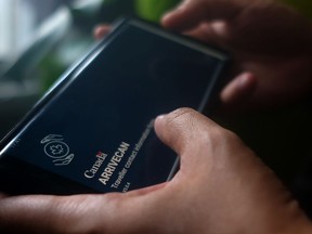 A person holds a smartphone set to the opening screen of the ArriveCan app.