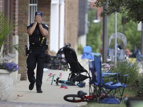 A Lake Forest, Ill., police officer walks down Central Ave in Highland Park, Ill., on Monday, July 4, 2022, after a shooter fired on the northern suburb's Fourth of July parade.