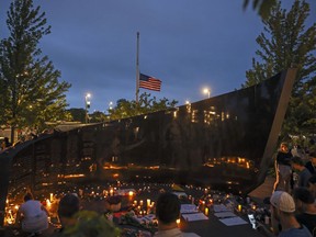 Dozens of mourners gather for a vigil near Central Avenue and St. Johns Avenue in downtown Highland Park, one day after a gunman killed at least seven people and wounded dozens more by firing an AR-15-style rifle from a rooftop onto a crowd attending Highland Park's Fourth of July parade, Tuesday, July 5, 2022 in Highland Park, Ill.. THE CANADIAN PRESS/Chicago Sun-Times-Anthony Vazquez&ampnbsp;via AP)