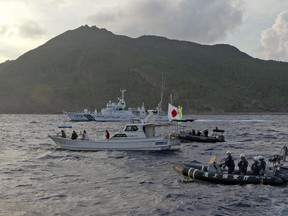 FILE - Japanese Coast Guard vessel and boats, rear and right, sail alongside a Japanese activists' fishing boat, center with a flag, near a group of disputed islands called Diaoyu by China and Senkaku by Japan, early Sunday, Aug. 18, 2013. Japan protested to Beijing after spotting Chinese and Russian warships just outside of Japanese territorial waters around the disputed East China Sea islands earlier Monday, July 4, 2022, prompting criticisms from China.