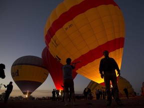 FILE - Tourists watch hot air balloons prepare to take off at dawn, on the west bank of the Nile River in Luxor, Egypt,April 1, 2016. Egyptian authorities on Wednesday, July 20, 2022, resumed hot air ballooning over the ancient city of Luxor following a two-day hiatus after two tourists were lightly injured during a ride.