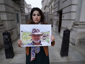 FILE - Roxanne Tahbaz holds a picture of her father Morad Tahbaz who is jailed in Iran, during a protest outside the Foreign, Commonwealth and Development Office in London, April 13, 2022. Morad Tahbaz, a U.K.-born environmentalist who has been jailed in Iran for more than four years, has been released on furlough, the British government said Wednesday, July 27, 2022. The 66-year-old wildlife conservationist is one of several people holding both Iranian and Western citizenship imprisoned by Iranian authorities over allegations of espionage.