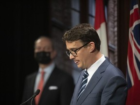 Ontario Labour Minister Monte McNaughton (right) takes to the podium as Finance Minister Peter Bethlenfalvy looks on, during a news conference in Toronto, on Wednesday April 28, 2021. Ontario is awaiting the details it needs to move ahead with offering "portable benefits" for workers without coverage, the returning labour minister says, and mulling next steps for a soon-to-expire sick leave program.