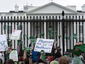 Abortion-rights demonstrators shout slogans after tying green flags to a fence at the White House during a protest to pressure the Biden administration to act and protect abortion rights, in Washington, Saturday, July 9, 2022.