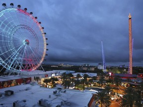 ICON Park attractions, The Wheel, left, Orlando SlingShot, middle, and Orlando FreeFall, right, are shown in Orlando, Fla., on March 24, 2022. The amusement park where a teenager fell from a ride and died earlier this year has paused a new sniper-like laser shooting game amid criticism in light of recent mass shootings. In a statement issued Saturday, July 16, 2022 park officials said some had questioned whether it was appropriate following mass shootings at a July 4 parade in a Chicago suburb, an elementary school in Ulvade, Texas and a grocery store in Buffalo, New York.