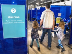 A man arrives with two young girls for his shot at the COVID-19 vaccination clinic at the Ontario Food Terminal in Toronto on Tuesday May 11, 2021. Federal officials say a COVID-19 vaccine for Canada's youngest children could be approved as soon as this month.THE CANADIAN PRESS/Frank Gunn