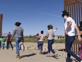FILE - A group of Brazilian migrants make their way around a gap in the U.S.-Mexico border in Yuma, Ariz., seeking asylum in the U.S. after crossing over from Mexico, June 8, 2021. Two Republican border-state governors who are investing billions of dollars on immigration enforcement and hours at the podium blasting the Biden administration policies have found two unlikely allies: Democratic mayors Muriel Bowser of Washington, D.C., and Eric Adams of New York. The mayors' recent overtures for federal aid is a response to Texas and Arizona busing migrants away from the border, a months-old practice that has been long on political theater and short on practical impact.