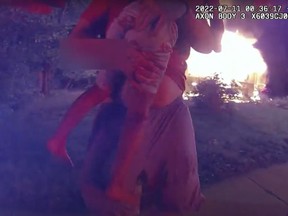 In this image taken from police bodycam video on July 11, 2022 and provided by the Lafayette, Ind., Police Department, Nick Bostic, 25, of Lafayette rescues a 6-year-old girl from a house fire in Lafayette, Ind. Bostic punched out a second-floor window and jumped out with the girl in his arms, sustaining multiple injuries, while the girl suffered a minor cut to her foot. He rescued four others from the house before that. (Lafayette Police Department via AP)