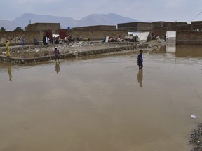 Boys wade through a flooded area on the outskirts of Quetta, Pakistan, Tuesday, July 5, 2022. At least six people, including women and children, were killed when the roofs of their homes collapsed in heavy rains lashing southwestern Pakistan and other parts of the country, a provincial disaster management agency said.