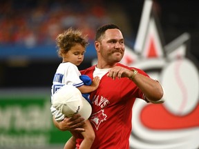 Former Toronto Blue Jays catcher Russell Martin with one of his daughters watches a video display of his time with the team after announcing his retirement from professional baseball before the game between the Blue Jays and the Tampa Bay Rays in Toronto on Friday, July 1, 2022.