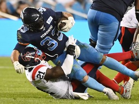 Toronto Argonauts running back Andrew Harris (33) is tackled by Montreal Alouettes linebacker Chris Ackie (21) during first second CFL football action in Toronto Thursday, June 16, 2022.