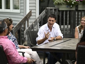 Prime Minister Justin Trudeau and Liberal MP Jenna Sudds speak with Reza Matin, left, and Shirin Mohseni, second from left, about the Climate Action Incentive Payment at their backyard in Ottawa, on Friday, July 15, 2022. Canadians who pay the federal carbon price got a midsummer money drop today with the first half of their annual "climate action incentive" payment deposited into their bank accounts.THE CANADIAN PRESS/Justin Tang