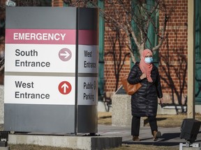 A woman walks past the Peter Lougheed Hospital in Calgary on Dec. 3, 2020. Calgary Mayor Jyoti Gondek says temporary night closures at Airdrie, Alta.'s urgent care centre will affect the entire region. Gondek says Calgary's busy hospitals already get patients from Airdrie and other communities around the city.