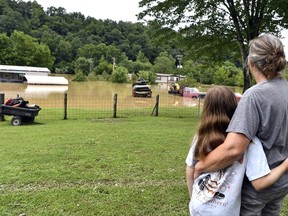 Bonnie Combs, right, hugs her 10-year-old granddaughter Adelynn Bowling watches as her property becomes covered by the North Fork of the Kentucky River in Jackson, Ky., Thursday, July 28, 2022. Flash flooding and mudslides were reported across the mountainous region of eastern Kentucky, where thunderstorms have dumped several inches of rain over the past few days.