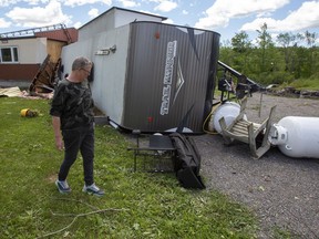 Lynn Prest walks beside her damaged house and overturned trailer from the aftermath of a possible tornado in Tweed, Ont., on Monday July 25, 2022.