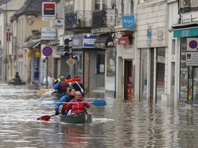 FILE - Residents evacuate their home in Nemours, 50 miles south of Paris, France, June 2, 2016. The European Central Bank has run a stress test on 104 banks, which concluded that Europe's banks aren't sufficiently considering risks from climate change and understanding the possible impact of floods, wildfires and losses on investments.