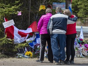 Eine Familie erweist den Opfern der Massenmorde an einem Kontrollpunkt in der Portapique Road in Portapique, NS, am Freitag, den 24.