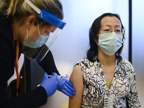 Registered nurse Clair Judd, left, vaccinates LTC nurse Yinghua Fang with the Pfizer-BioNTech COVID-19 mRNA vaccine during the COVID-19 pandemic in Toronto on Tuesday, December 15, 2020. COVID-19 outbreaks more than doubled in Ontario long-term care homes in the first week of July, Public Health Ontario says, as the sector sees the impact of a seventh virus wave.THE CANADIAN PRESS/Nathan Denette