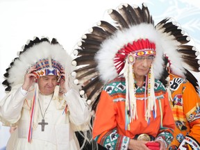 Pope Francis adjusts a traditional headdress he was given after his apology to Indigenous people during a ceremony in Maskwacis, Alta., as part of his papal visit across Canada on Monday, July 25, 2022.