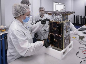 Rebecca Rogers, systems engineer, left, takes dimension measurements of the CAPSTONE spacecraft in April 2022, at Tyvak Nano-Satellite Systems, Inc., in Irvine, Calif. NASA said Tuesday, July 5, that it has lost contact with a $32.7 million spacecraft headed to moon to test out a lopsided lunar orbit, but agency engineers are hopeful they can fix the problem.