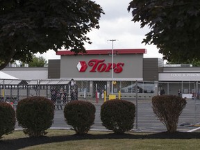 People stand in the parking lot of the Tops Friendly Market on Thursday, July 14, 2022, in Buffalo, N.Y. The Buffalo supermarket where 10 Black people were killed by a white gunman is set to reopen its doors, two months after the racist attack.