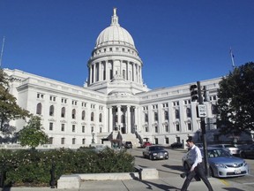 FILE - This Oct. 10, 2012, file photo shows a man walking by the Wisconsin state Capitol in Madison. The Wisconsin Supreme Court's conservative majority ruled on Thursday, July 7, 2022, that a transgender woman cannot change her name because she is on the state's sex offender registry and the law does not allow people on the registry to change their names.