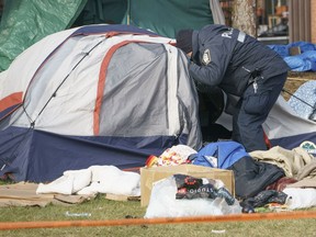 Parks Canada's decision to hold a series of events dubbed learn-to-camp in the heart of Montreal faced backlashes after groups working with people without a home called it a "double standard." A police officer checks for people in a tent in Montreal, on Monday, December 7, 2020.