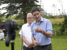 Prime Minister Justin Trudeau speaks to the media, as Minister of Veterans Affairs and Associate Minister of National Defence Lawrence MacAulay looks on, after he toured a park in Stratford, Prince Edward Island on Friday July, 22, 2022.
