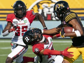 Hamilton Tiger Cats wide receiver Tim White (12) pushes off defending Ottawa Redblacks defensive back Ranthony Texada (16) during first half CFL football game action in Hamilton, Ont. on Saturday, July 16, 2022.