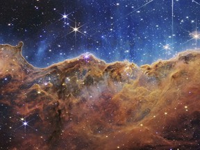 This image released by NASA on Tuesday, July 12, 2022, shows the edge of a nearby, young, star-forming region NGC 3324, in the Carina Nebula. Captured in infrared light by the Near-Infrared Camera (NIRCam) on the James Webb Space Telescope, this image reveals previously obscured areas of star birth, according to NASA.