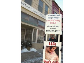 FILE - An abortion protester stands outside the Red River Valley Women's Clinic in Fargo, N.D., on Feb. 20, 2013. North Dakota's only abortion clinic, the Red River Women's Clinic, has gone to federal court seeking to declare the state's imminent abortion ban is contrary to the state constitution.