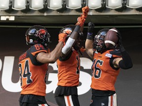 BC Lions' Bryan Burnham (right) celebrates with teammates Keon Hatcher (left) and Dominique Rhymes after scoring a touchdown against the Toronto Argonauts during first half of CFL football action in Vancouver on June 25, 2022.