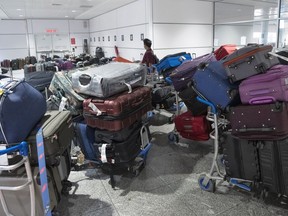 A passenger looks for his luggage among a pile of unclaimed baggage at Pierre Elliott Trudeau airport in Montreal on June 29, 2022.