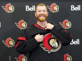 Veteran forward Claude Giroux pulls on an Ottawa Senators sweater in Ottawa on Wednesday, July 13, 2022, after signing a 3-year contract with the team.