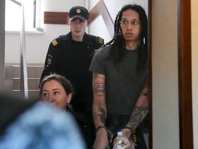 FILE - WNBA star and two-time Olympic gold medalist Brittney Griner is escorted to a courtroom for a hearing, in Khimki just outside Moscow, Russia, Monday, June 27, 2022. U.S. basketball star Brittney Griner is set to go on trial in a Moscow-area court Friday July 1. The proceedings that are scheduled to begin Friday come about 4 1/2 months after she was arrested on cannabis possession charges at an airport while traveling to play for a Russian team.