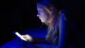 young woman using the smart phone on bed before sleep