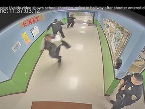 In this photo from surveillance video provided by the Uvalde Consolidated Independent School District via the Austin American-Statesman, authorities retreat down a hallway after gunfire is heard in a classroom at Robb Elementary School in Uvalde, Texas, Tuesday, May 24, 2022. (Uvalde Consolidated Independent School District/Austin American-Statesman via AP)