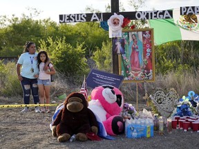 Mourners visit a make-shift memorial to honor the victims and survivors of the recent human smuggling tragedy, Wednesday, July 6, 2022, in San Antonio. All but six of the 53 migrants found dead or dying in a tractor-trailer last week have been identified.
