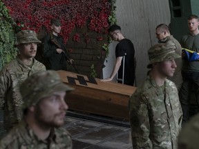 Soldiers of the Azov regiment pay their last respects to a serviceman killed in battle against Russian troops, in a city crematorium in Kyiv, Ukraine, Thursday, July 21, 2022.