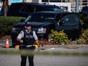 Bullet holes are seen in the windshield and passenger window of a police vehicle at the scene of a shooting, in Langley, B.C., on Monday, July 25, 2022. A suspect is in custody after "several people" were shot in the Metro Vancouver city of Langley, RCMP said. Police issued a blaring cellphone alert at about 6:20 Monday morning, saying they were at the scenes of several shootings "involving transient victims."
