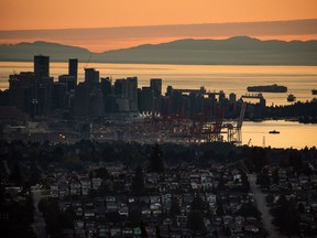 A Seabus passenger ferry, right, travels across Burrard Inlet at sunset as downtown Vancouver and the port are seen from Burnaby Mountain, on Monday, July 11, 2022.