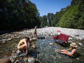 People cool off in the frigid Lynn Creek water in North Vancouver, B.C., on Monday, June 28, 2021. The Public Safety Ministry says another hot spell is moving into British Columbia and it advises residents to have a heat plan ready as the mercury begins to climb this weekend.